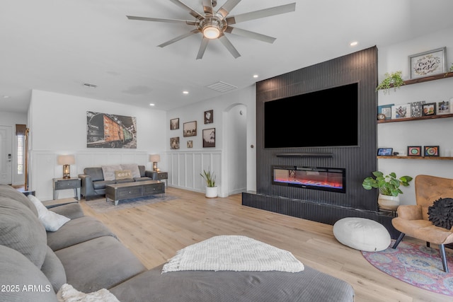 living area with visible vents, wood finished floors, ceiling fan, recessed lighting, and a large fireplace