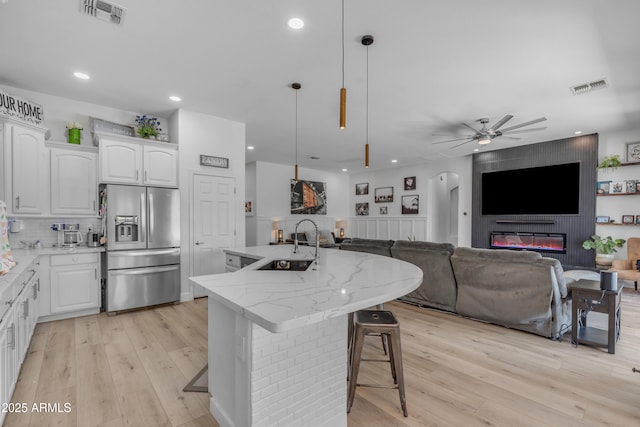 kitchen with stainless steel fridge, a sink, light wood finished floors, and visible vents