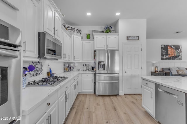 kitchen featuring recessed lighting, light stone counters, white cabinets, and stainless steel appliances