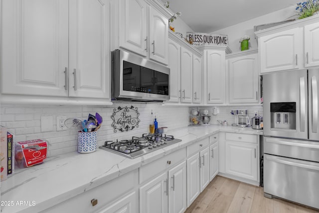 kitchen featuring white cabinets, stainless steel appliances, and tasteful backsplash