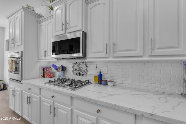 kitchen featuring appliances with stainless steel finishes, backsplash, and white cabinetry