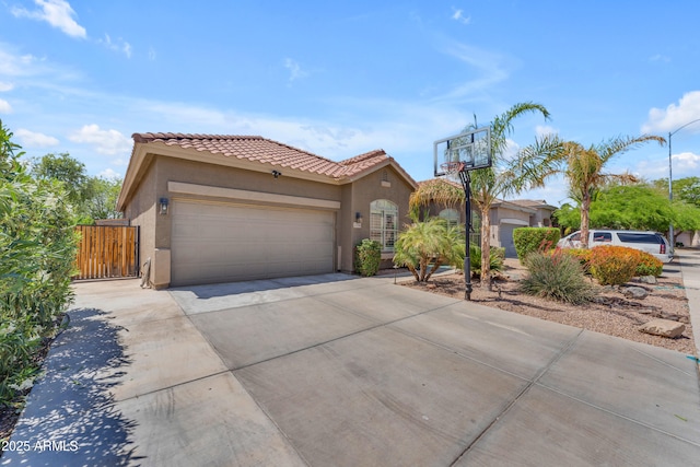 view of front facade with fence, an attached garage, stucco siding, concrete driveway, and a tiled roof
