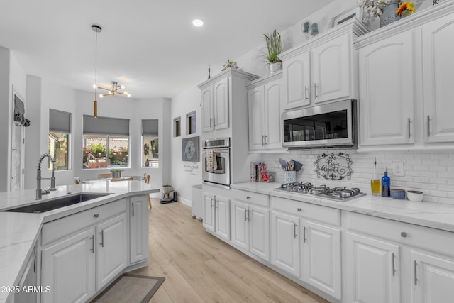 kitchen with a sink, backsplash, white cabinets, and stainless steel appliances