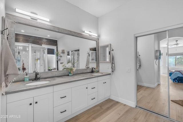 bathroom featuring double vanity, a sink, baseboards, and wood finished floors
