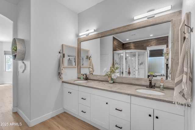 full bathroom featuring double vanity, a sink, wood finished floors, and a shower stall