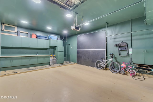 garage with recessed lighting, freestanding refrigerator, and a garage door opener