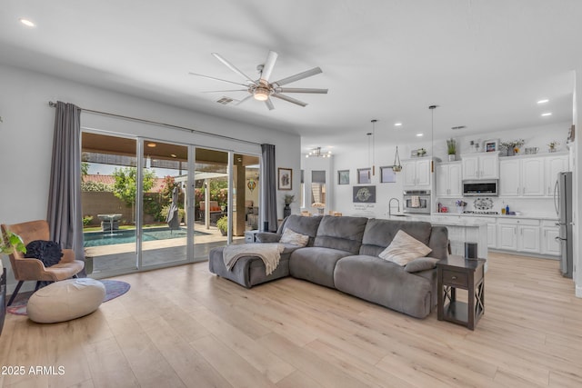 living room featuring ceiling fan with notable chandelier, recessed lighting, light wood-style flooring, and visible vents