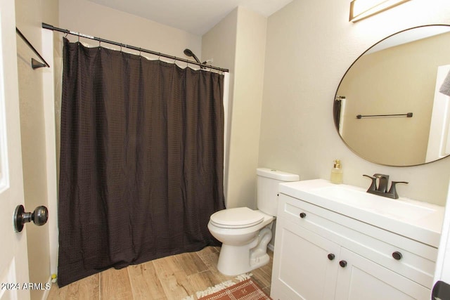 bathroom featuring curtained shower, hardwood / wood-style floors, toilet, and vanity