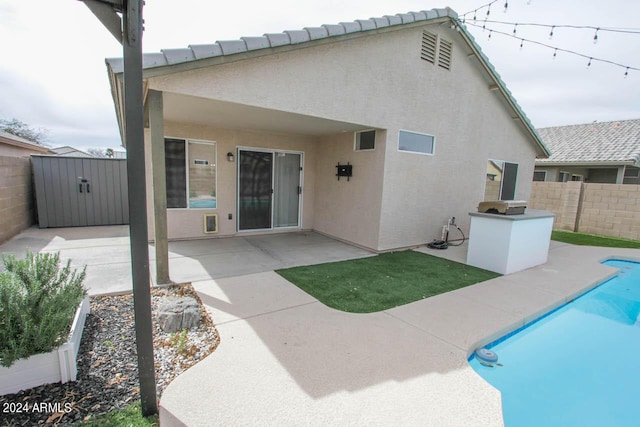 rear view of property featuring a fenced in pool and a patio