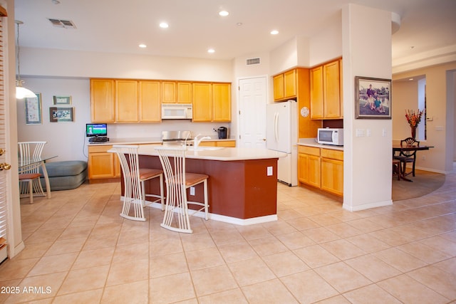 7413 E Russet Sky Dr, Scottsdale, AZ 85266 - kitchen featuring white appliances, an island with sink, light countertops, light tile patterned floors, and a breakfast bar area