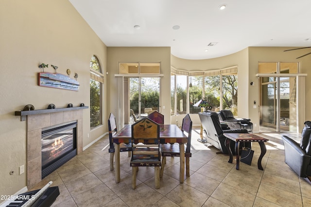 tiled dining room with ceiling fan and a tile fireplace