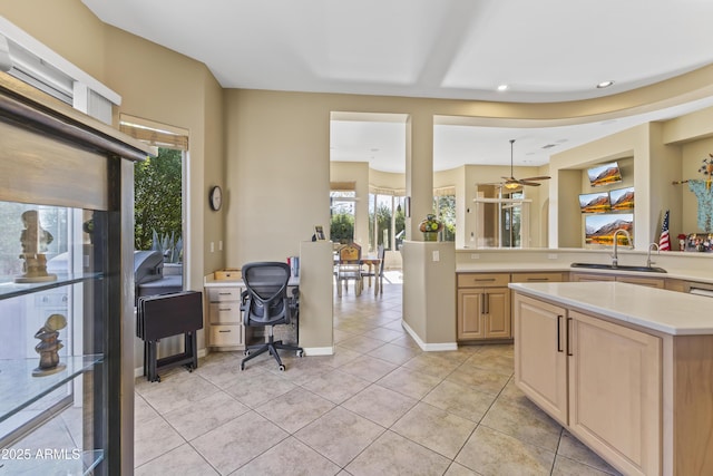 kitchen with light brown cabinetry, sink, light tile patterned floors, a kitchen island, and ceiling fan