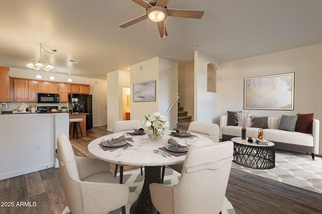 dining space featuring dark hardwood / wood-style flooring and ceiling fan with notable chandelier