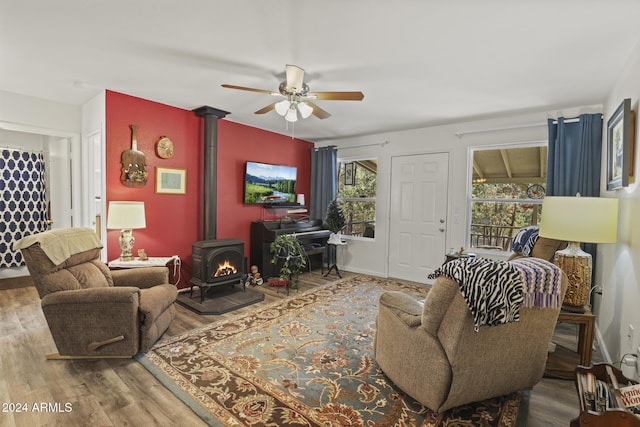 living room with hardwood / wood-style flooring, ceiling fan, and a wood stove