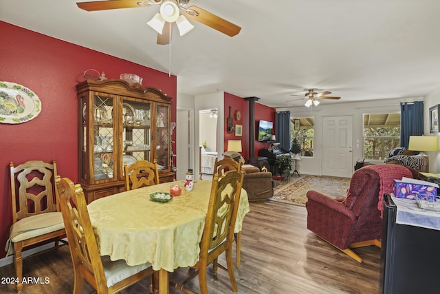 dining room featuring a wood stove, ceiling fan, and hardwood / wood-style floors