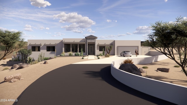 pueblo revival-style home featuring stucco siding, driveway, fence private yard, and an attached garage