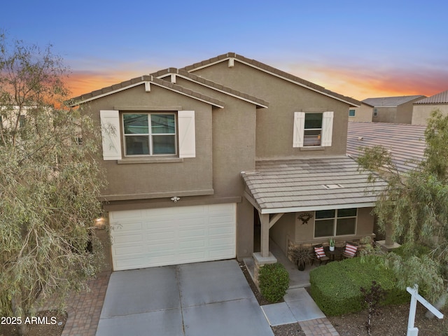 traditional home with an attached garage, driveway, and stucco siding