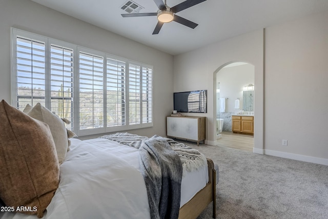 bedroom featuring ceiling fan, ensuite bath, and light colored carpet