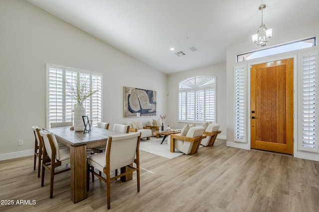 dining area featuring an inviting chandelier, plenty of natural light, lofted ceiling, and light wood-type flooring