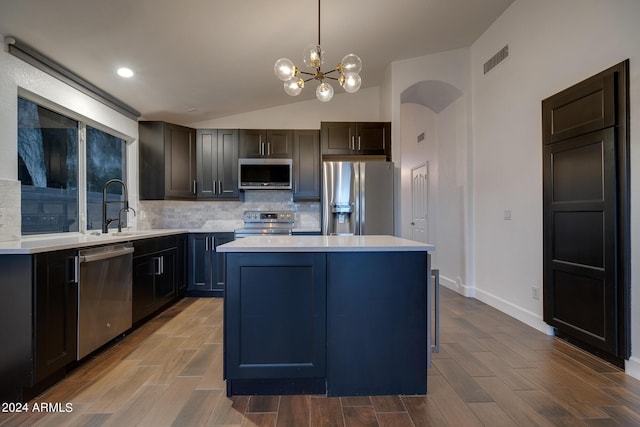 2203 E Crest Ln, Phoenix, AZ 85024 - kitchen featuring appliances with stainless steel finishes, decorative backsplash, light countertops, a center island, and vaulted ceiling