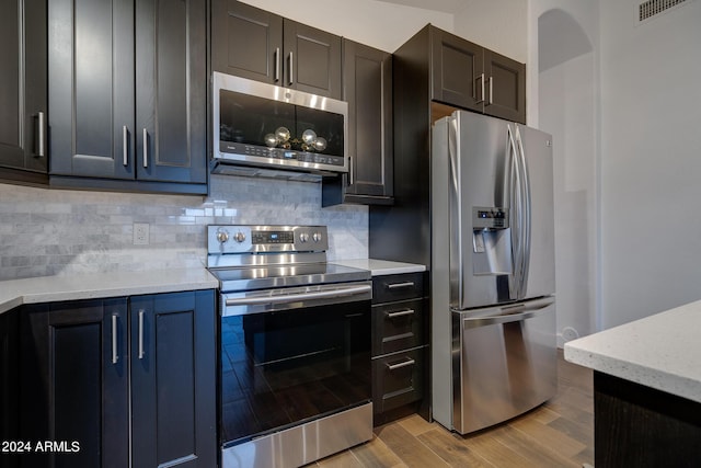 2203 E Crest Ln, Phoenix, AZ 85024 - kitchen with appliances with stainless steel finishes, light wood finished floors, decorative backsplash, and light stone countertops