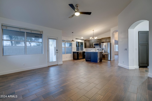 2203 E Crest Ln, Phoenix, AZ 85024 - unfurnished living room with a ceiling fan, arched walkways, lofted ceiling, dark wood finished floors, and a chandelier
