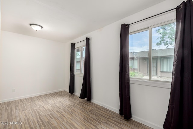 empty room with light wood-style flooring, baseboards, and a healthy amount of sunlight