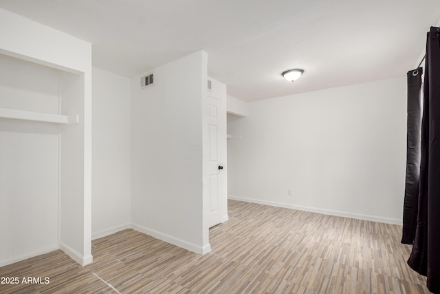 interior space featuring baseboards, visible vents, and wood finished floors
