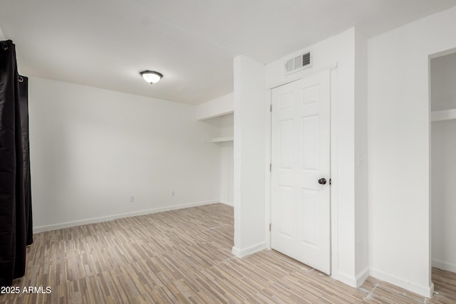unfurnished bedroom with baseboards, light wood-style flooring, and visible vents