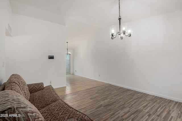 unfurnished living room featuring vaulted ceiling, a chandelier, baseboards, and wood finished floors