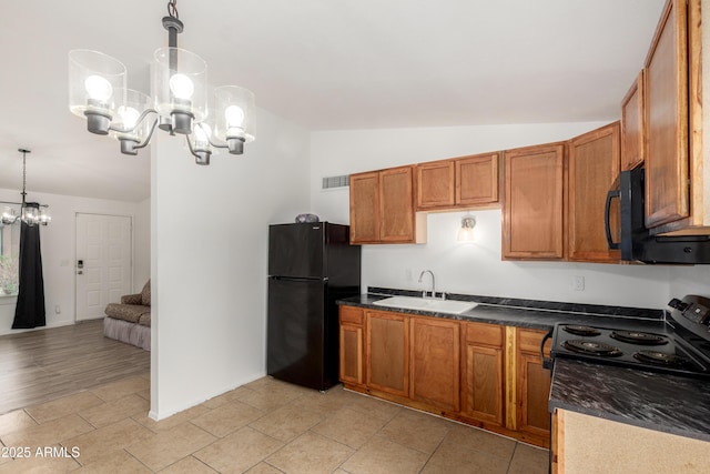 kitchen with a sink, brown cabinetry, lofted ceiling, black appliances, and a notable chandelier