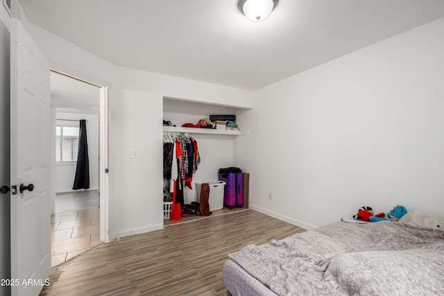 bedroom with a closet, wood finished floors, and baseboards
