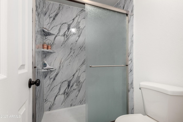 bathroom with toilet and a marble finish shower