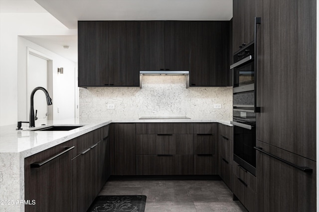 kitchen featuring backsplash, modern cabinets, a sink, light stone counters, and black appliances