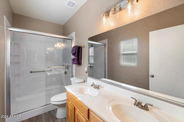 bathroom featuring wood-type flooring, toilet, vanity, and an enclosed shower