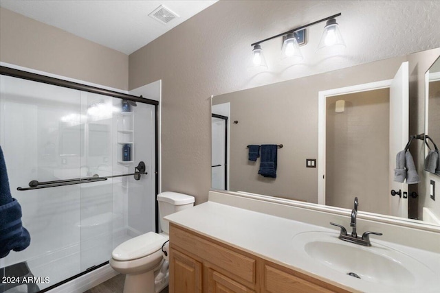 bathroom featuring vanity, toilet, and an enclosed shower