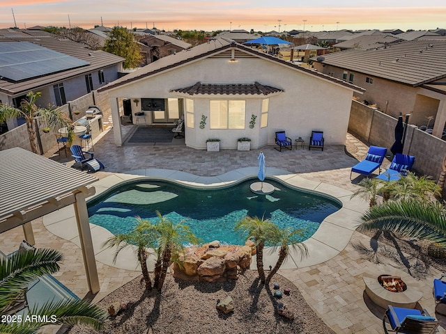 pool at dusk with a patio area, an outdoor fire pit, a fenced in pool, and a fenced backyard