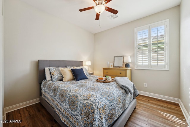 bedroom featuring visible vents, ceiling fan, baseboards, and wood finished floors