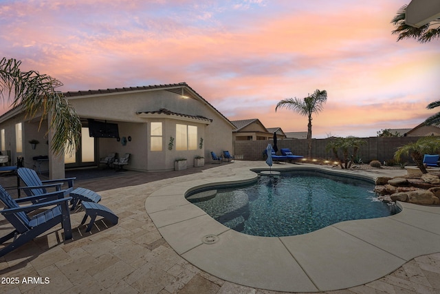 pool at dusk featuring a patio area, a fenced backyard, and a fenced in pool