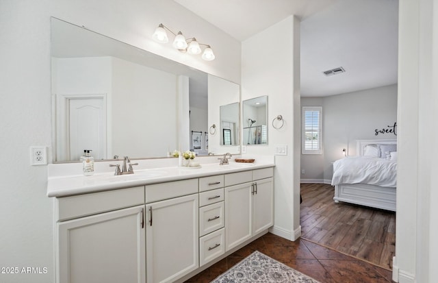 ensuite bathroom with double vanity, a sink, visible vents, and connected bathroom