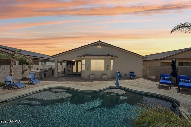 rear view of house with a patio area, a fenced backyard, a fenced in pool, and stucco siding