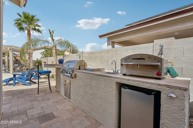 view of patio / terrace with area for grilling, a sink, fence, exterior kitchen, and a pergola