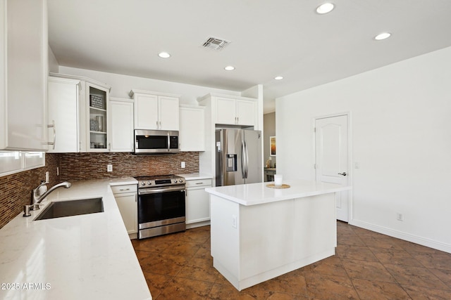 kitchen featuring a center island, tasteful backsplash, visible vents, appliances with stainless steel finishes, and a sink