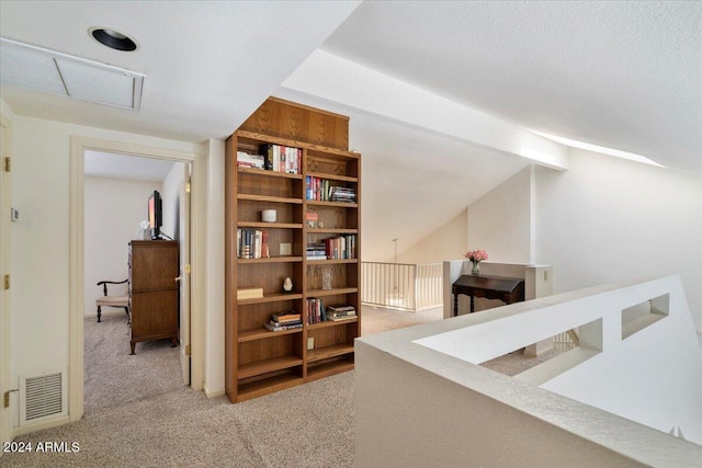 hall featuring light carpet, vaulted ceiling with beams, and a textured ceiling