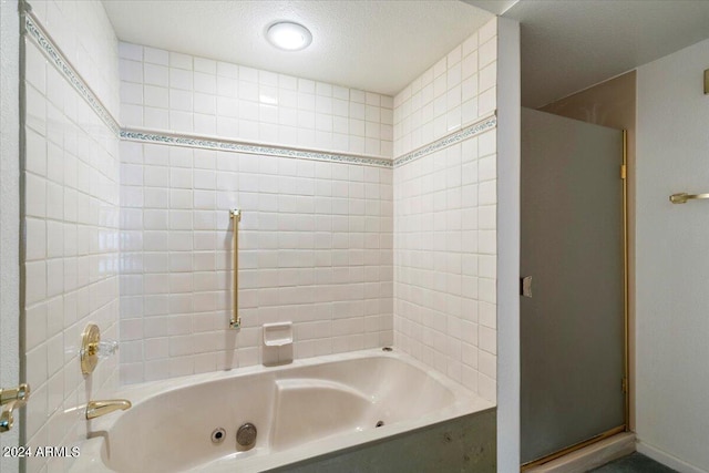 bathroom with independent shower and bath and a textured ceiling