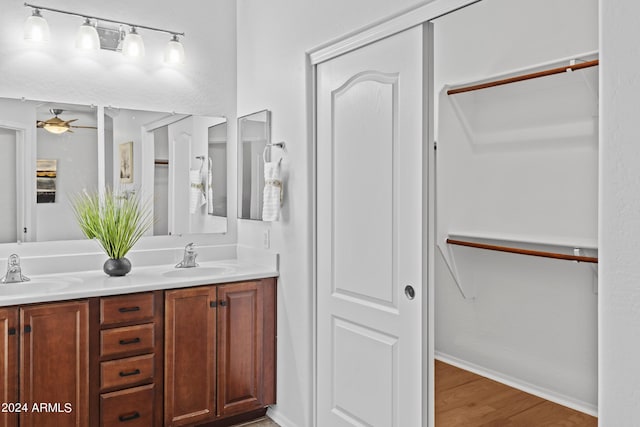 full bathroom featuring a ceiling fan, a sink, double vanity, and wood finished floors