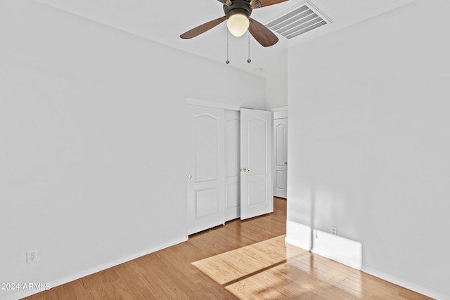 unfurnished bedroom with a closet, a ceiling fan, visible vents, baseboards, and wood finished floors