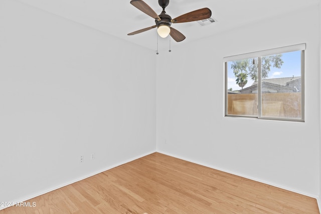 unfurnished room featuring a ceiling fan, visible vents, light wood-style flooring, and baseboards