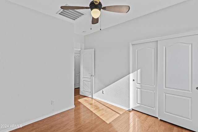 unfurnished bedroom with light wood-style flooring, a closet, ceiling fan, baseboards, and visible vents
