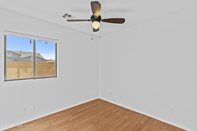 spare room featuring a ceiling fan, visible vents, wood finished floors, and baseboards